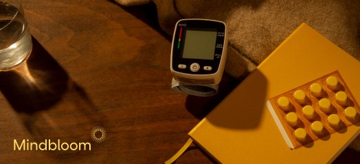 journal, blood pressure measuring tool, pills and a journal on the table with mindbloom logo